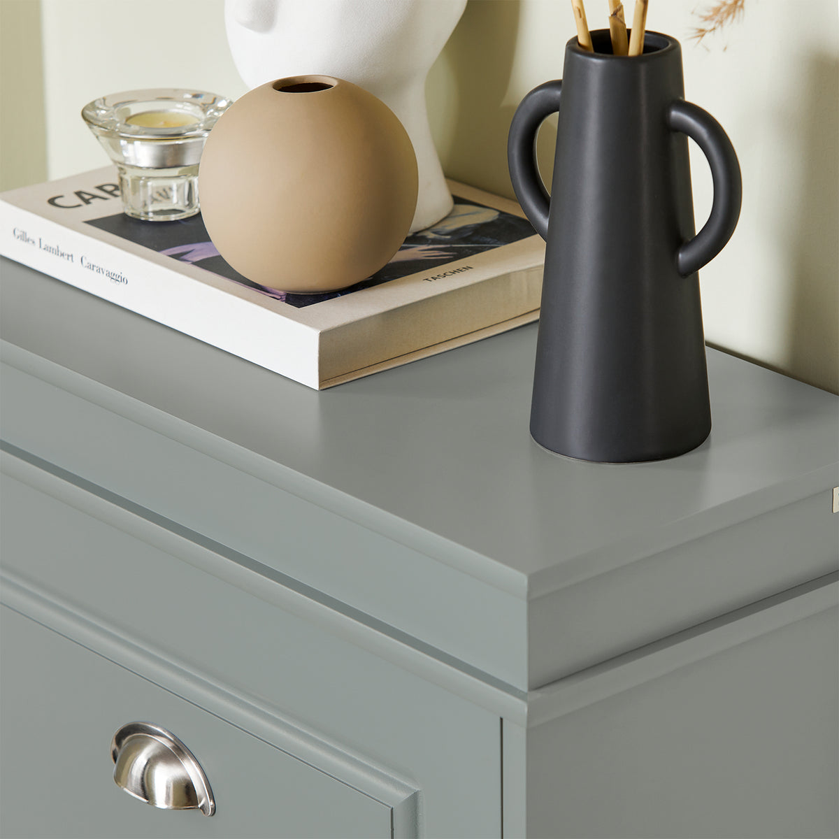 Top surface of grey shoe cupboard used as hallway display shelf.